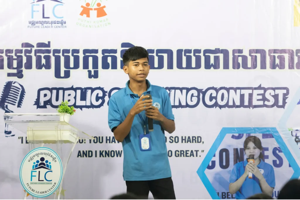 phann samet Phann Samet speaking into a microphone in front of an FLC public speaking contest banner.